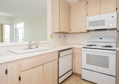 Cocina luminosa y limpia con electrodomésticos blancos y gabinetes de madera clara, impecable tras el servicio de North Shore Cleaning