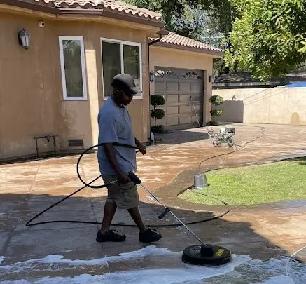 Empleado de Dust N Shine realizando limpieza a presión en el patio exterior, dejando el área impecable.