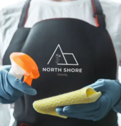 Empleado de North Shore Cleaning con guantes y equipo de limpieza, listo para ofrecer un servicio profesional.