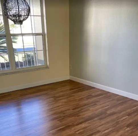Habitación vacía con suelo de madera laminada y una gran ventana, en una casa en Orlando, demostrando los espacios bien mantenidos gracias a los servicios de limpieza de casas en la ciudad