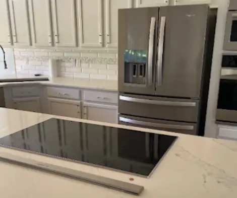 Cocina moderna y limpia en Orlando con encimera de mármol blanco, estufa integrada y refrigerador de acero inoxidable, reflejando los resultados de un servicio profesional de limpieza de casas en Orlando